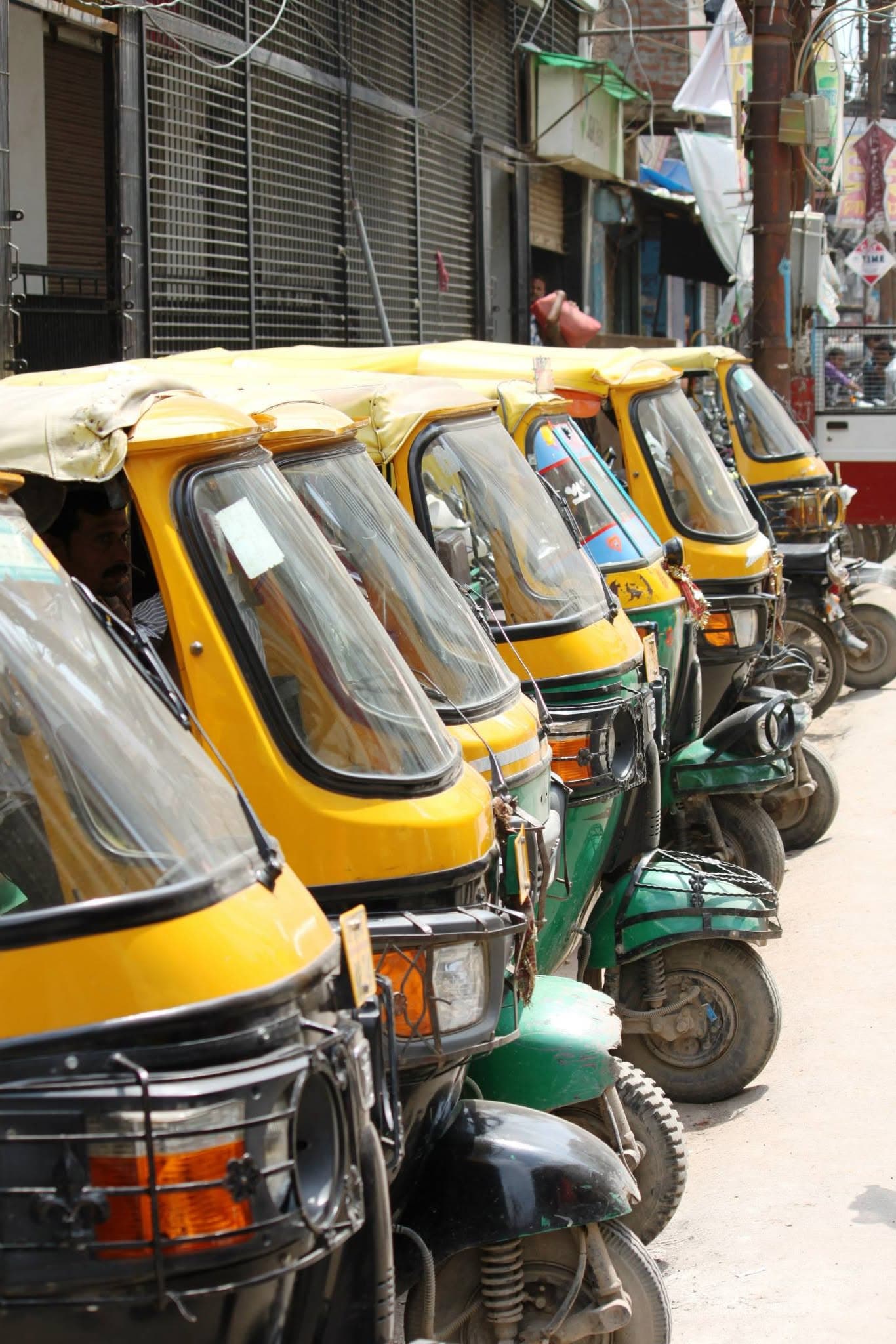 A row of yellow and green auto rickshaws in Delhi, photographed during the India trip